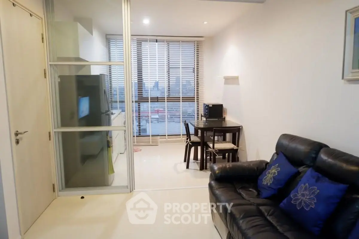 Modern living room with sleek furniture and city view through large windows.