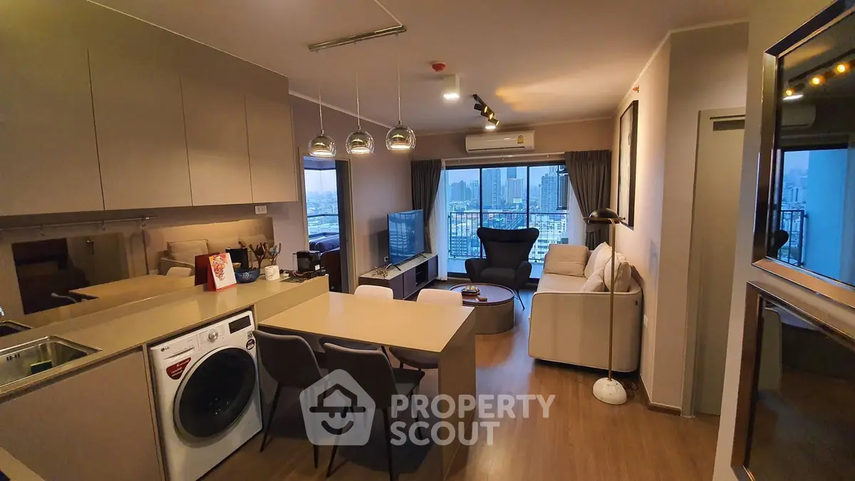 Modern open-layout living room with city view, featuring stylish furniture and built-in kitchen appliances.