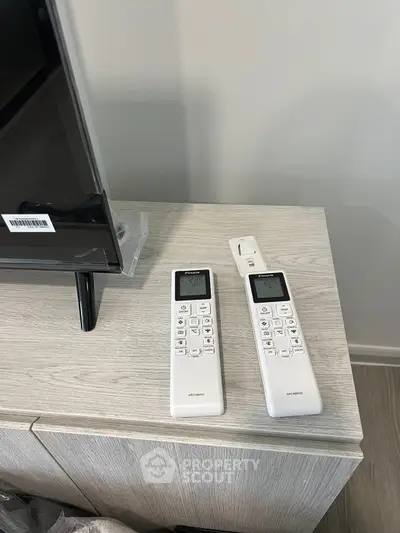 Modern living room with sleek TV stand and remote controls on a stylish wooden cabinet.