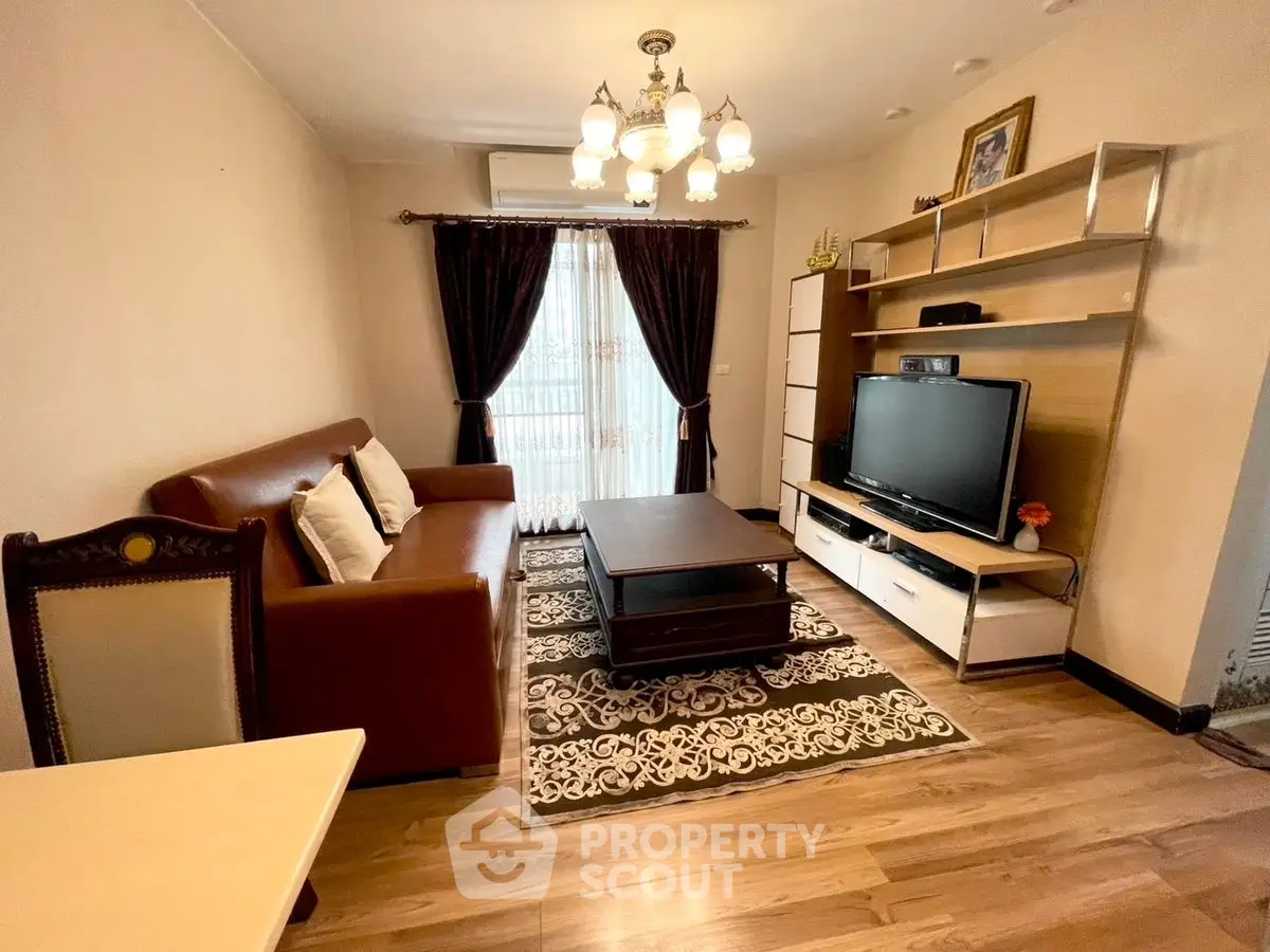Cozy living room with elegant chandelier and modern entertainment center.