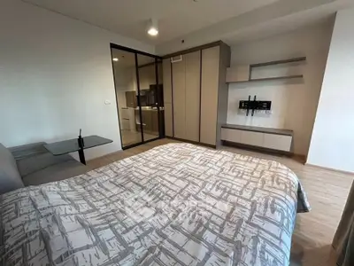 Modern bedroom with stylish decor and glass partition leading to kitchen area.