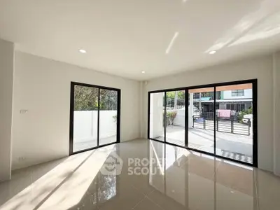 Spacious modern living room with large windows and glossy tile flooring, offering abundant natural light and garden view.