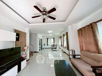 Spacious living room with modern decor and ceiling fan, perfect for family gatherings.