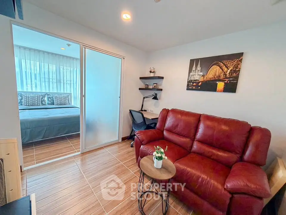 Cozy living room with red leather sofa and view into modern bedroom