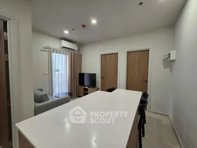 Modern living room with sleek furniture and open layout, featuring a large TV and stylish decor.