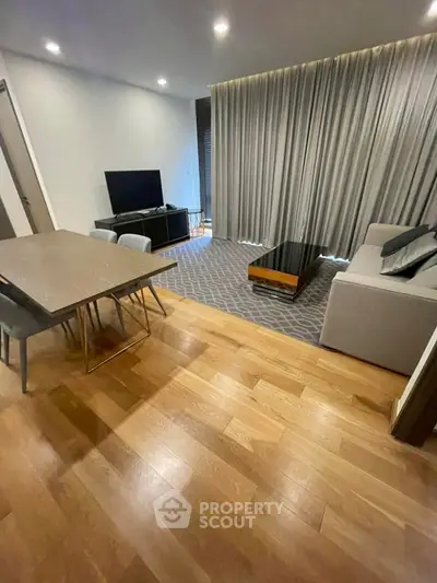 Modern living room with wooden flooring, stylish furniture, and elegant curtains.