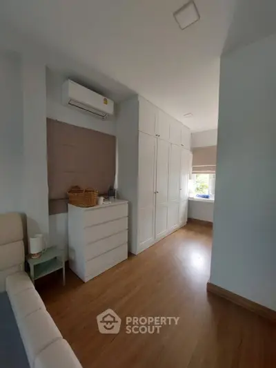 Spacious bedroom with wooden flooring and ample natural light