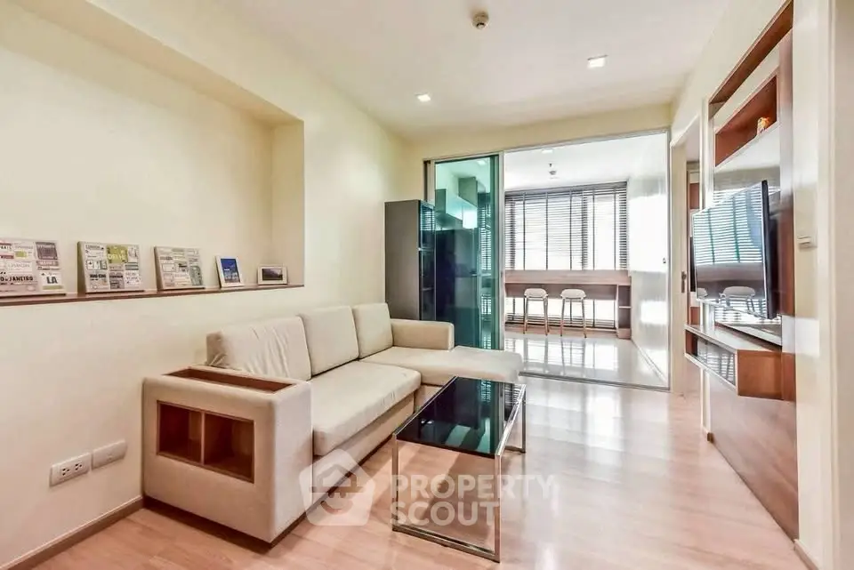 Modern living room with sleek furniture and open layout, featuring a glass coffee table and built-in shelving.