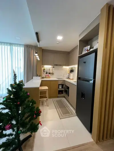 Modern kitchen with sleek design and Christmas tree, featuring open layout and contemporary appliances.