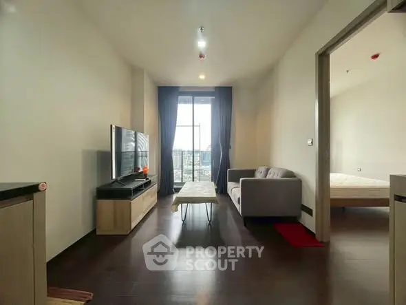 Modern living room with sleek furniture and large window offering natural light.