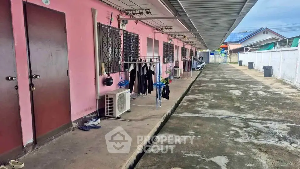 Charming pink exterior of a row of apartments with outdoor laundry area and air conditioning units.