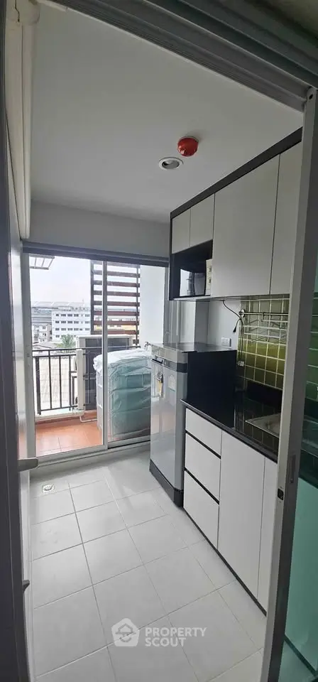 Modern kitchen with sleek cabinets and balcony view in urban apartment