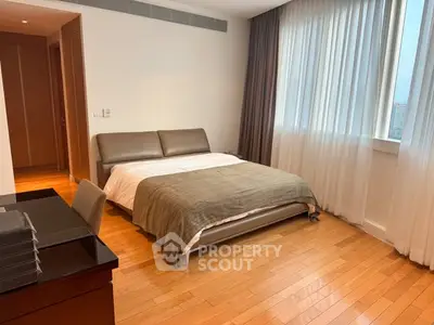 Spacious bedroom with modern furnishings and large window for natural light.