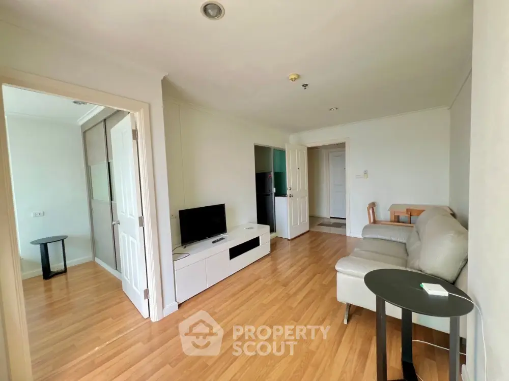 Spacious living room with modern decor and wooden flooring in a cozy apartment.
