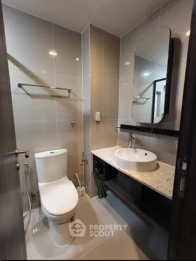 Modern bathroom with sleek fixtures and elegant design, featuring a large mirror and contemporary sink.