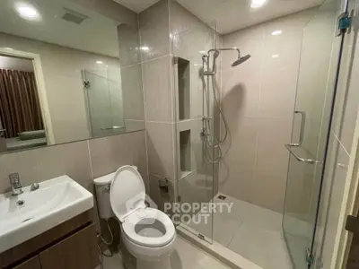 Modern bathroom with glass shower and sleek fixtures in a contemporary apartment.