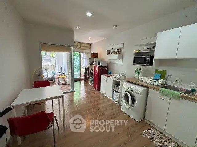 Modern open-layout kitchen with washing machine and balcony access in cozy apartment.
