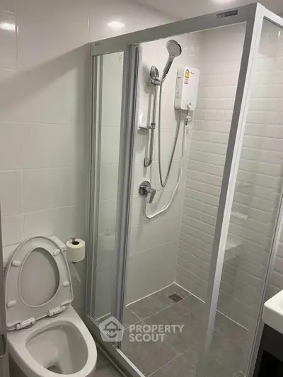 Modern bathroom with glass shower enclosure and white fixtures in a compact space.