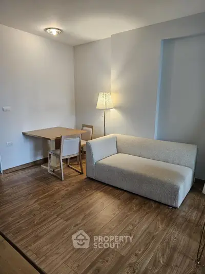 Modern living room with cozy sofa and dining area, featuring elegant wooden flooring.
