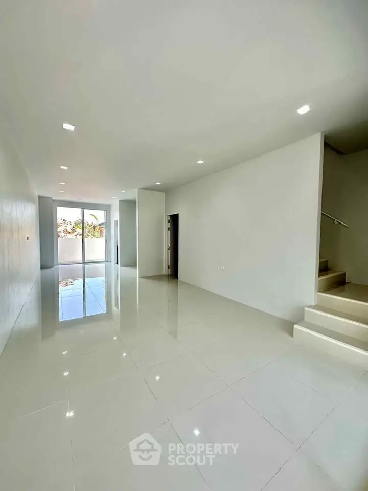 Spacious modern living room with glossy tile flooring and large windows for natural light.