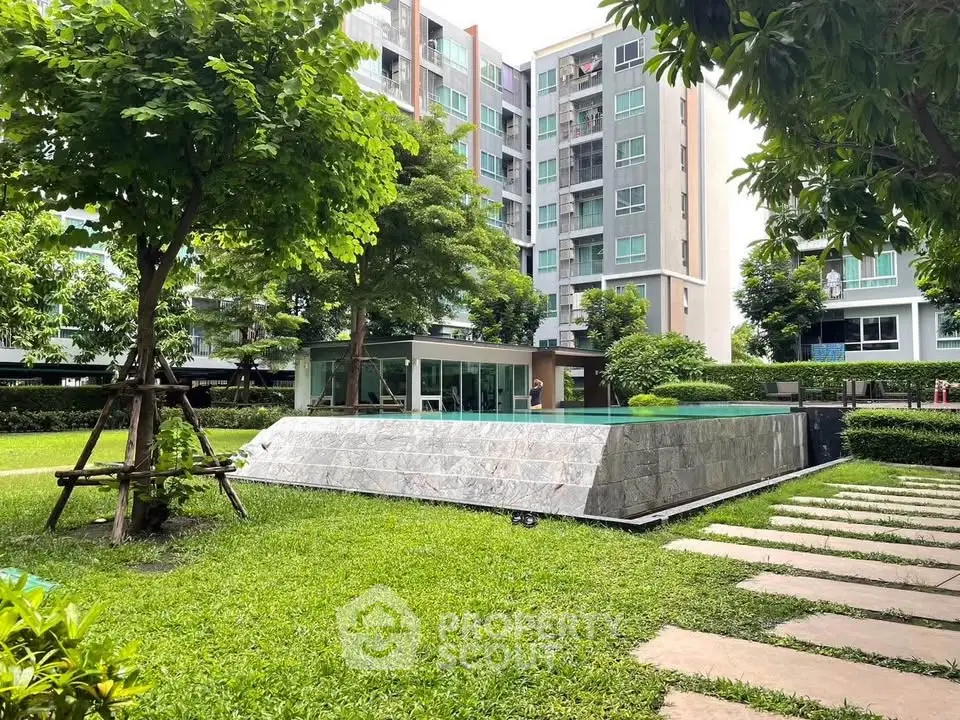 Modern apartment complex with lush garden and pool view, ideal for urban living.