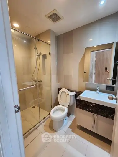 Modern bathroom with glass shower and sleek vanity in contemporary apartment.