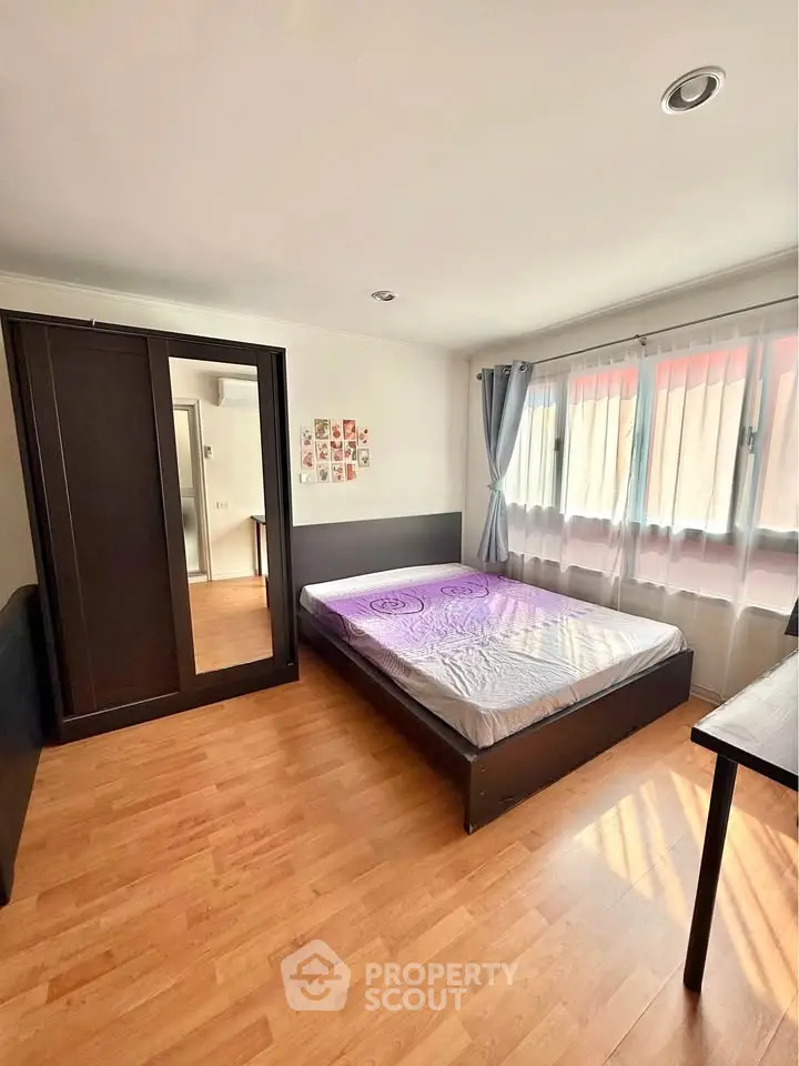 Spacious bedroom with large windows and wooden flooring