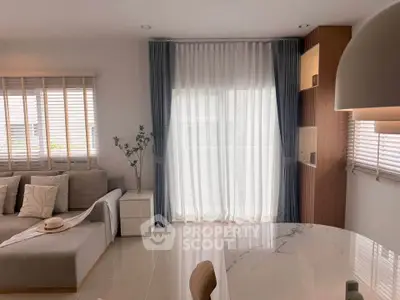 Elegant living room with modern decor, featuring a cozy sofa, stylish curtains, and a chic dining area.