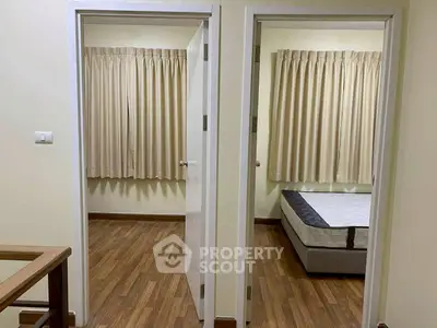 Cozy interior view of a home with two adjacent rooms featuring wooden flooring and neutral curtains.