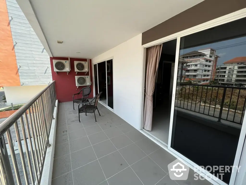 Spacious balcony with outdoor seating area, overlooking urban surroundings, perfect for relaxation and entertaining guests in a modern apartment setting.