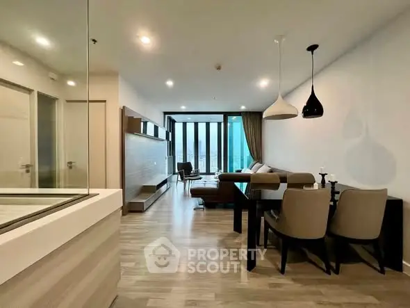 Spacious modern living room with elegant dining area and stylish lighting fixtures.