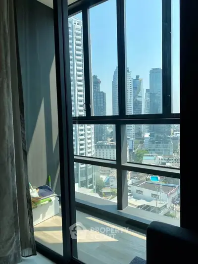 Stunning city view from modern high-rise apartment balcony with floor-to-ceiling windows.