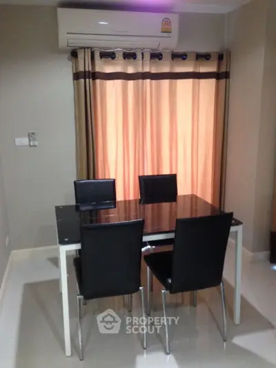 Modern dining area with sleek table and chairs under air conditioning unit.
