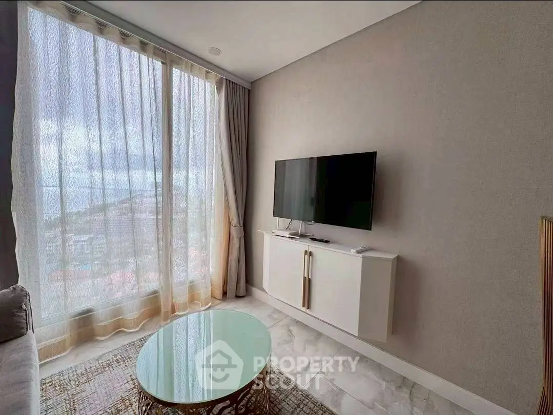 Modern living room with large window and wall-mounted TV, offering a bright and airy atmosphere.