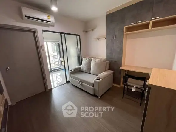 Modern living room with cozy sofa and workspace, featuring sleek design and natural light.