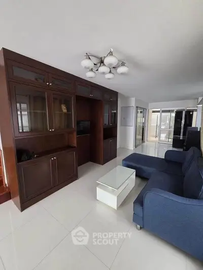 Spacious living room with elegant wooden cabinetry and modern blue sofa in a bright apartment.