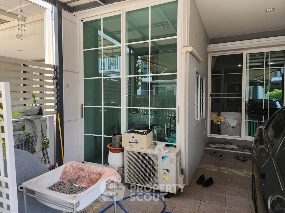 Modern home exterior with glass enclosure and outdoor air conditioning unit.