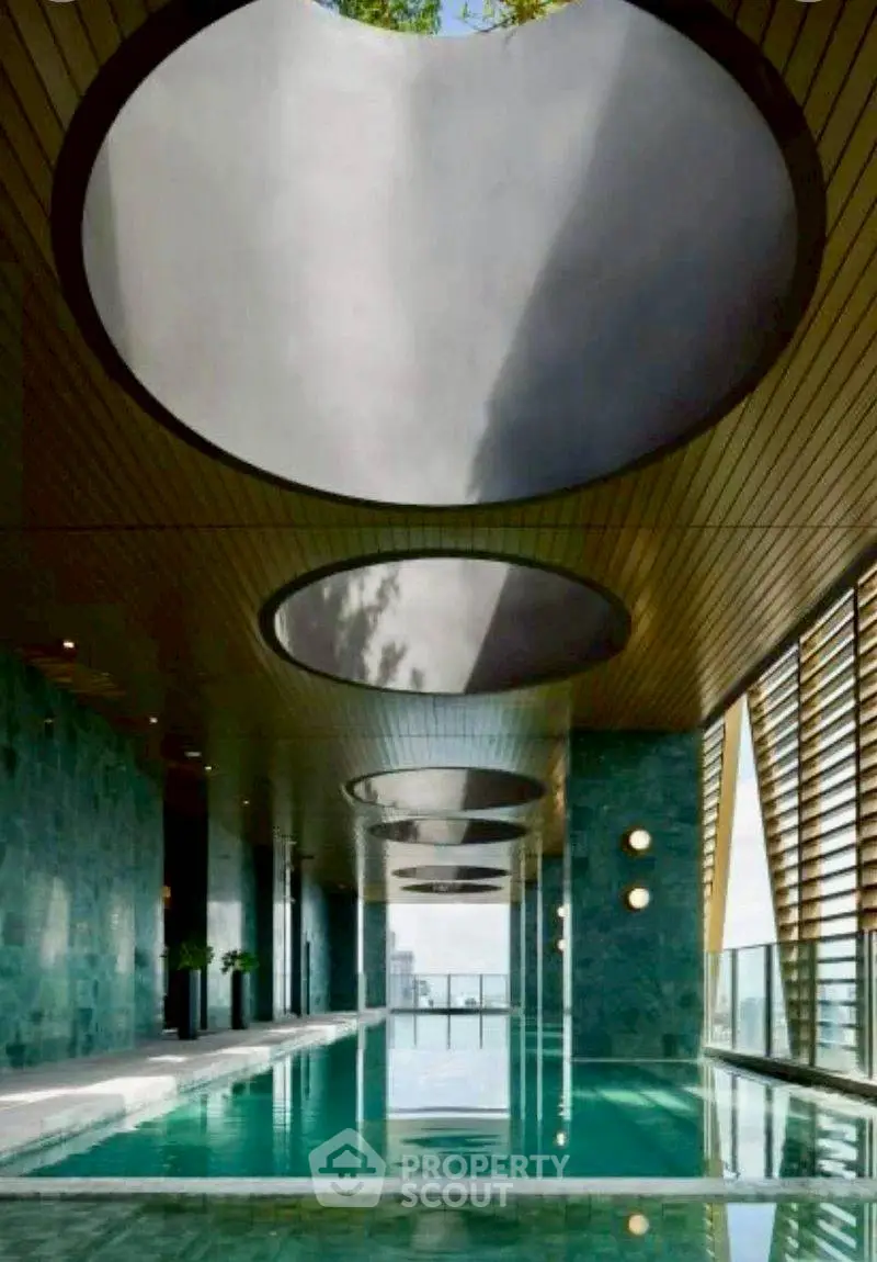 Luxurious indoor pool with modern architectural design and skylights.