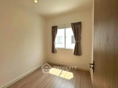 Bright empty bedroom with wooden floor and window with curtains