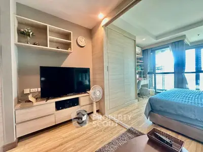 Modern bedroom with TV and sliding door to balcony, featuring stylish decor and natural light.