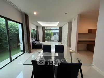 Spacious modern living room with glass dining table and garden view, perfect for family gatherings.