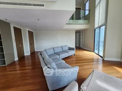 Spacious modern living room with high ceilings and large windows offering city views.