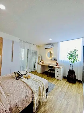 Modern bedroom with stylish decor and workspace, featuring wooden flooring and natural light.