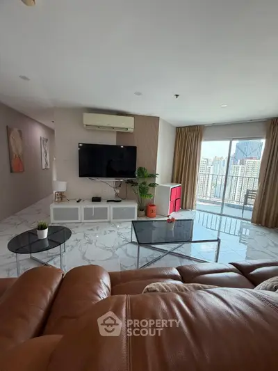 Spacious living room with modern decor and city view, featuring leather sofa and large TV.
