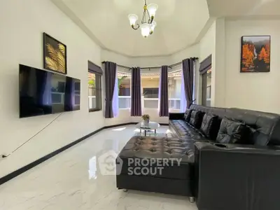 Spacious living room with modern black leather sofa and wall-mounted TV, featuring elegant decor and ample natural light.