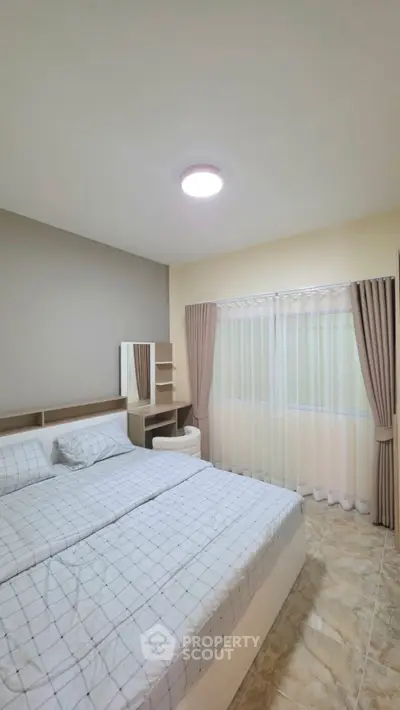 Spacious bedroom with modern decor and ample natural light, featuring elegant curtains and a comfortable bed.