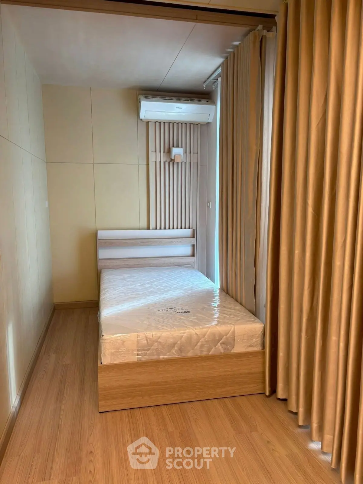 Cozy small bedroom with wooden flooring and air conditioning