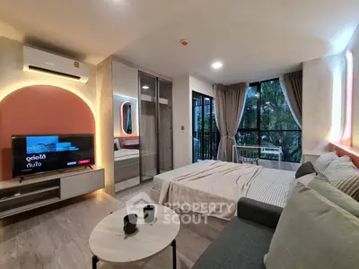 Modern studio apartment with cozy living area and large windows overlooking greenery.