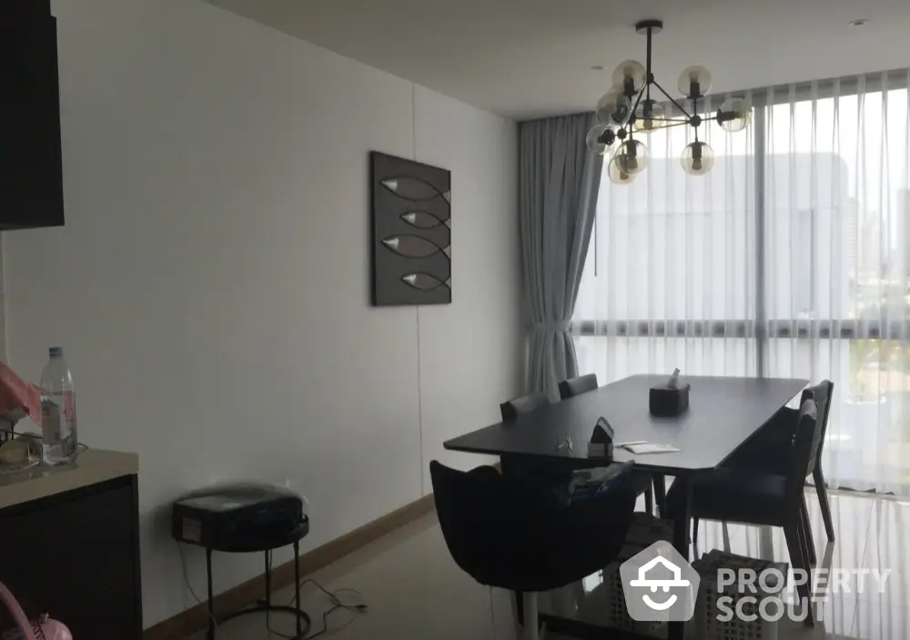 Modern dining area with stylish chandelier and large window view.