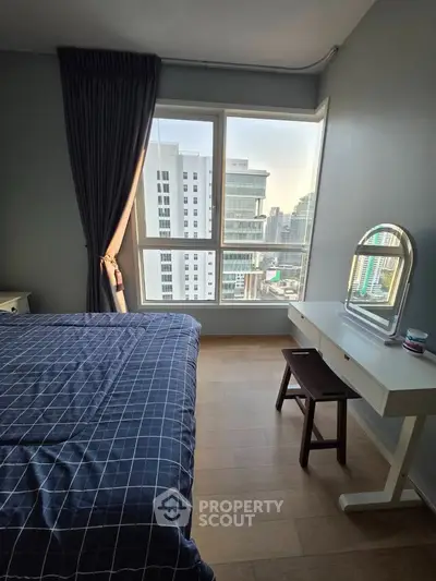 Modern bedroom with city view, featuring a stylish bed and vanity desk, perfect for urban living.